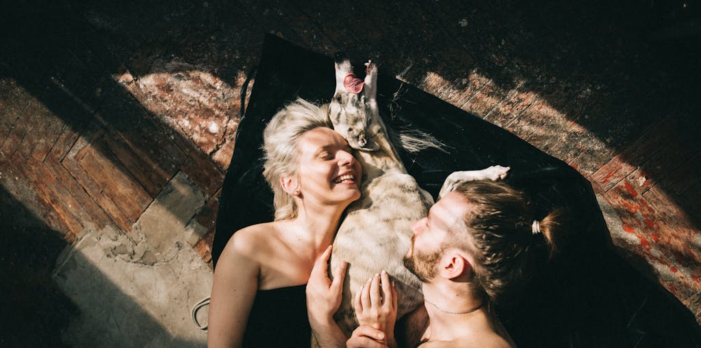 Couple Lying Down and Hugging their Dog