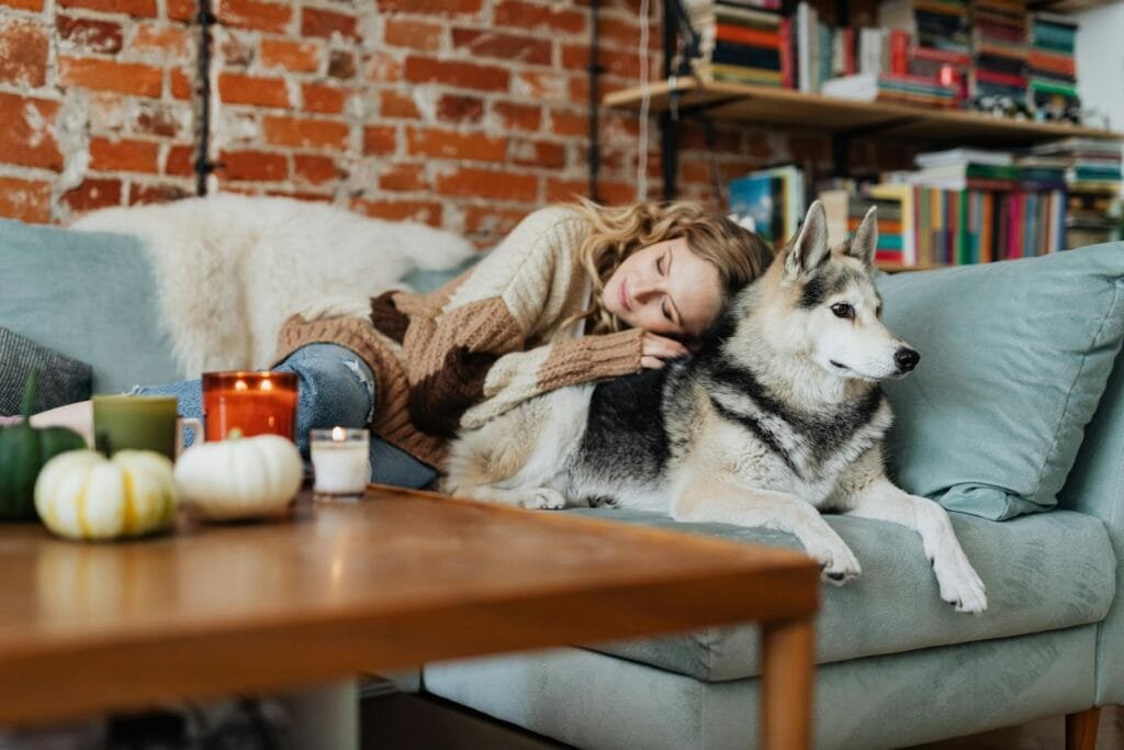 Woman resting with her dog in a cozy living room setting, evoking warmth and comfort.